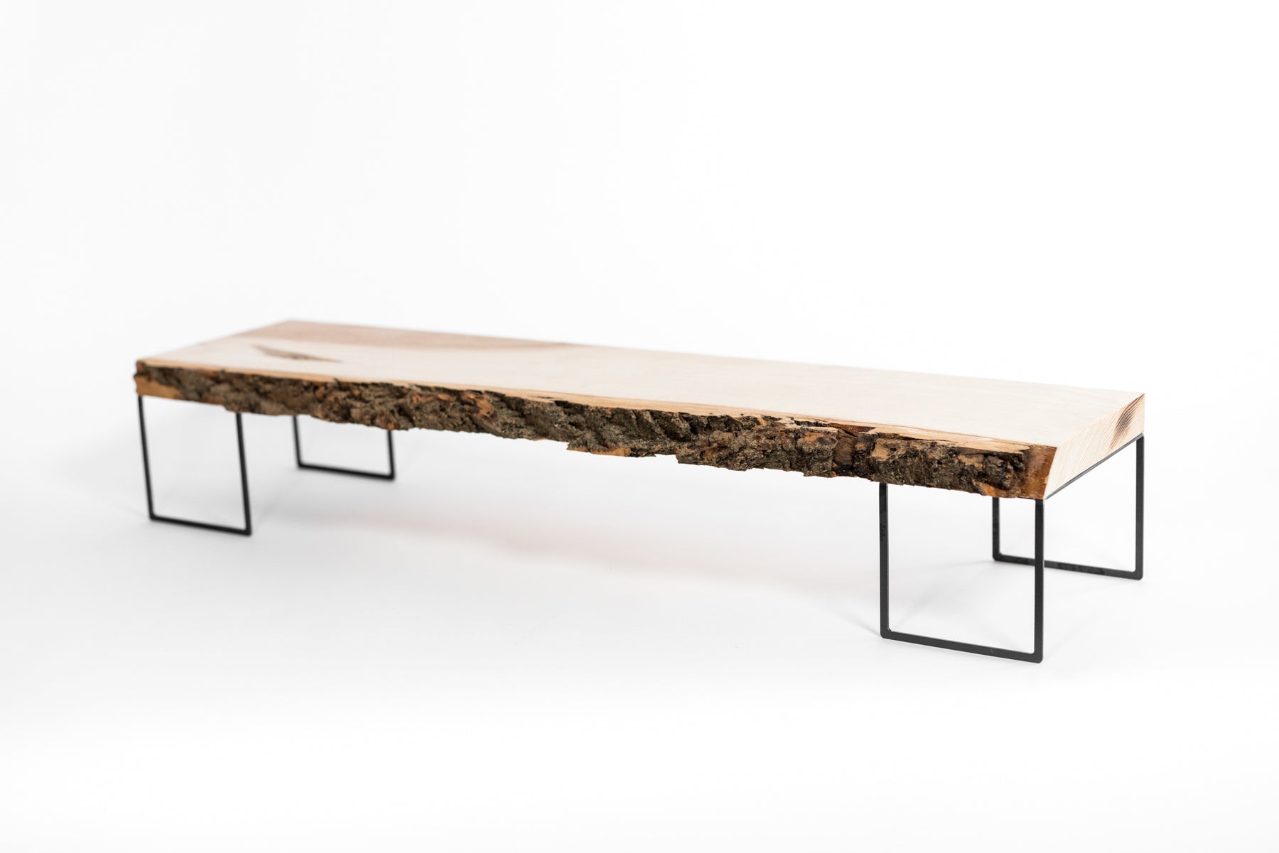 Minimalist wooden monitor stand with a natural bark edge, supported by slender black metal legs.