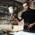 EWART WOODS craftsman using a spray gun to paint wooden furniture in workshop
