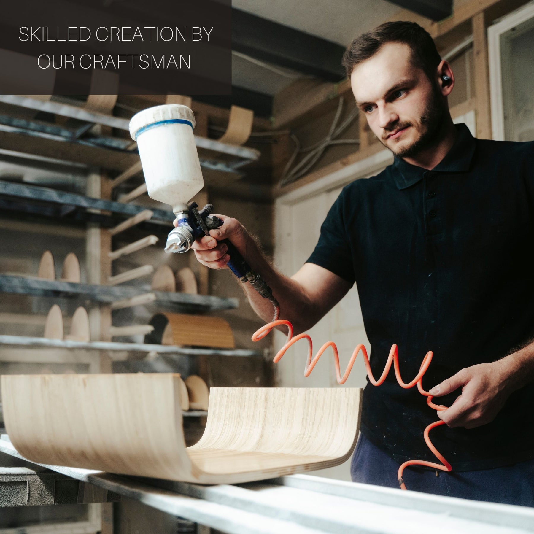 EWART WOODS craftsman using a spray gun to paint wooden furniture in workshop