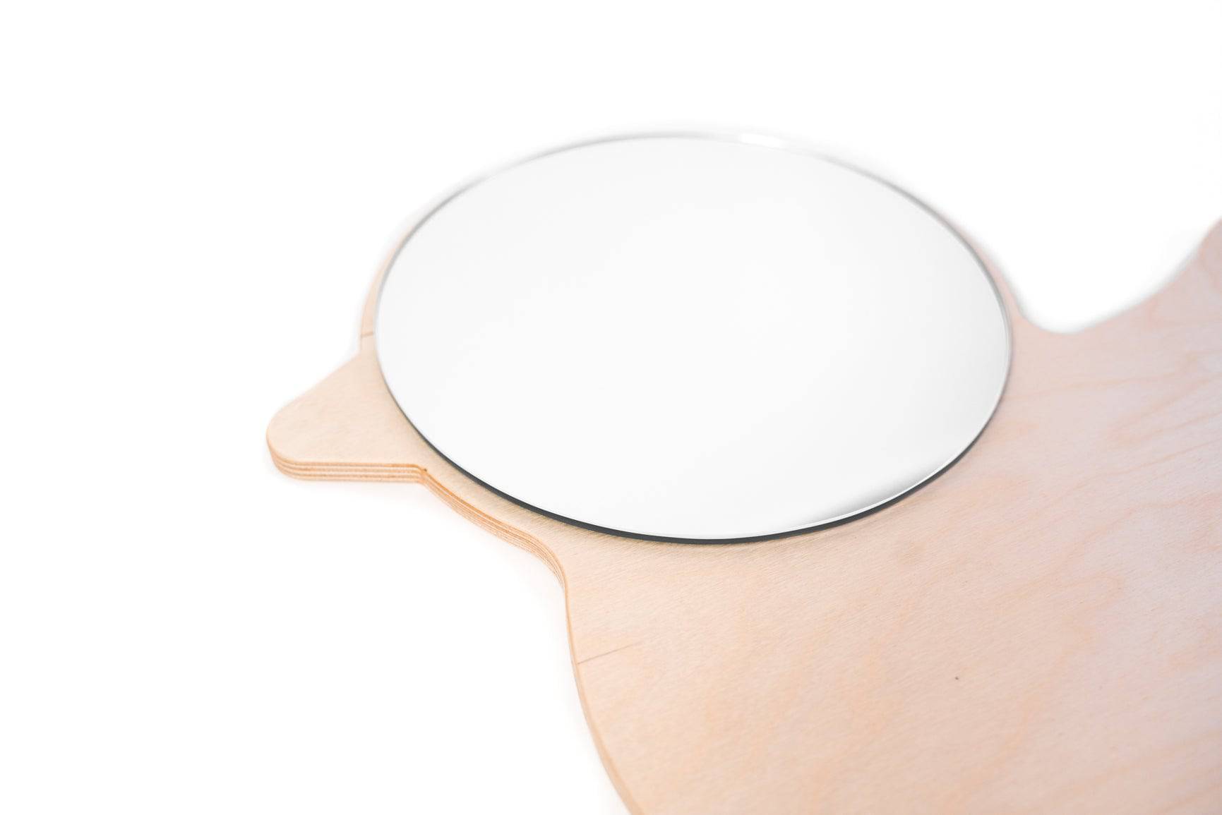 Side view of a duck-shaped wooden mirror, featuring a smooth, layered wood frame and a round reflective surface.