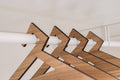 Close-up of wooden hangers in paldau finish with a geometric design, featuring sharp edges and a smooth texture, hanging on a closet rod.
