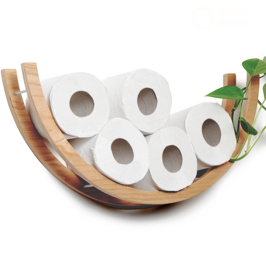 Close-up of a wooden half-circle toilet paper holder, displaying five rolls of toilet paper. The holder is made of light wood with a smooth texture, complemented by a plant on the side.