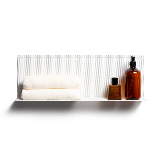 Minimalist perforated metal wall shelf holding two folded white towels, a small brown bottle, and a larger amber pump bottle, showcasing a clean and organized look.