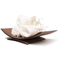 Walnut curved wooden holder with rolled white towels and decorative flowers, isolated on white.