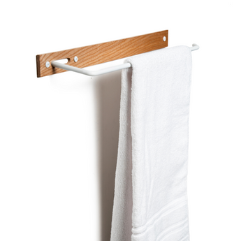 Wall-mounted wooden towel rack with a textured wood surface, white metal bar, visible screws, and a white towel.