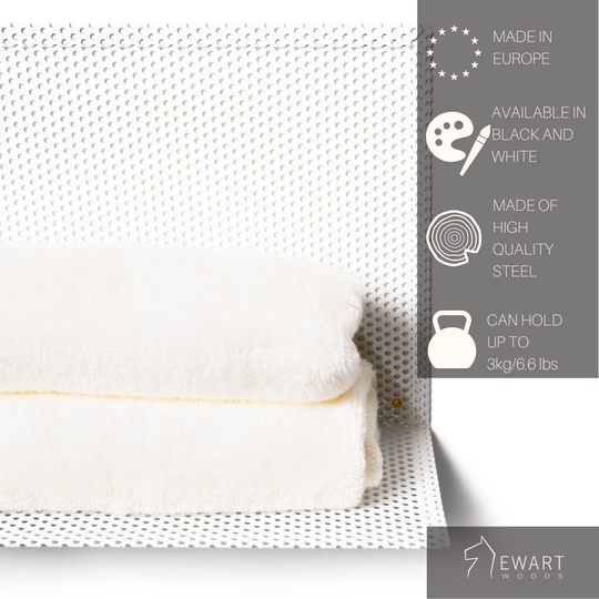 Perforated metal wall shelf with folded towels, labeled as European-made, high-quality steel, and holds up to 3 kg. EWART WOODS logo included.