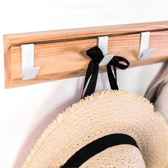 Close-up of wall mounted wood hanger with metal hooks