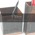Two rustic metal utensil holders with wooden bases, holding pens. The image features the logo &