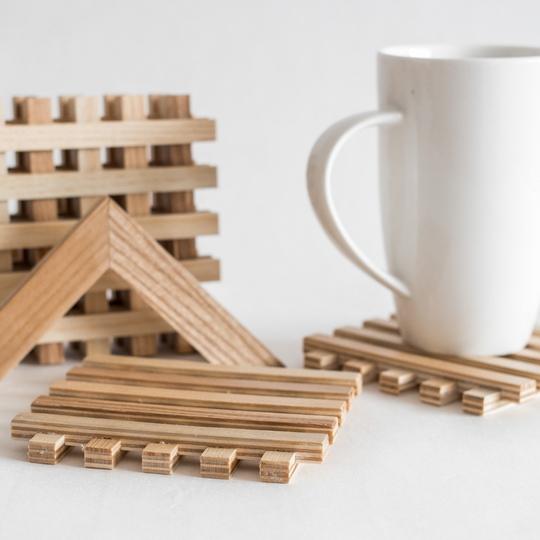 Handmade wooden coasters with a unique lattice design, holding a cup, complete with a pyramid-shaped holder.