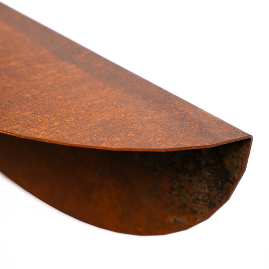 Close-up of a curved metal shelf with a rustic, oxidized finish, showcasing its textured surface and edges.