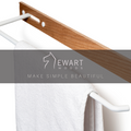 Wooden towel rack with a white metal bar, visible screws, and a white towel. The image includes the EWART WOODS logo with the slogan Make Simple Beautiful.