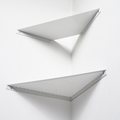 Two minimalist white wall-mounted shelves in a corner, one solid and the other perforated metal, arranged in a geometric style.