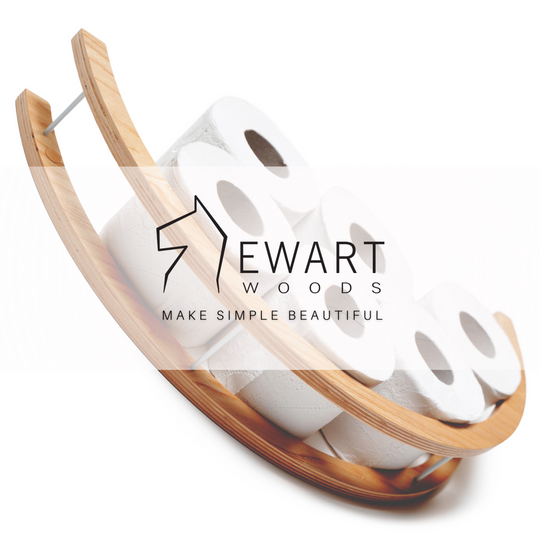 Close-up of a wooden half-circle toilet paper holder, displaying several rolls of toilet paper. The EWART WOODS logo and the slogan MAKE SIMPLE BEAUTIFUL.