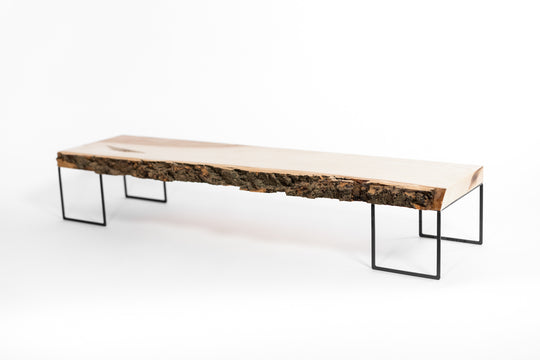 Minimalist wooden monitor stand with a natural bark edge, supported by slender black metal legs.