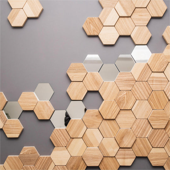Hexagonal wooden wall tiles combined with mirrored accents create a geometric, modern decor pattern on a grey background.