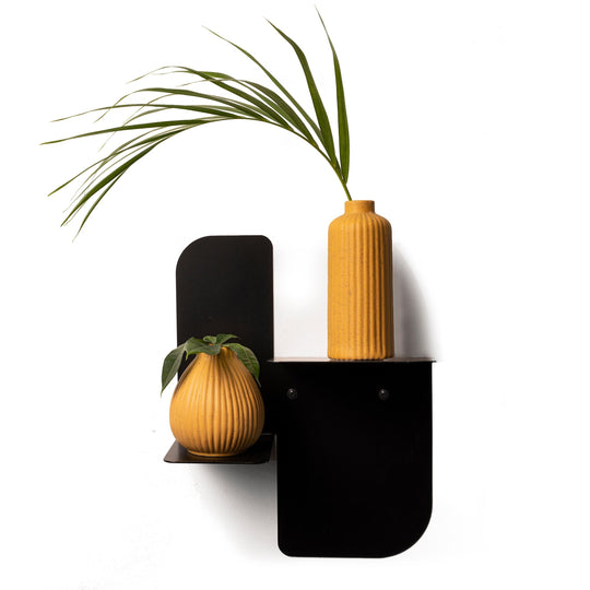 Modern dual-tier black metal shelf, featuring a tall, grooved orange vase on the top tier and a round, patterned orange vase with greenery on the lower tier. The shelf is secured with visible screws, adding a sleek and stylish element to the design.