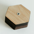 Close-up of the back of a hexagonal wooden key holder, showing a metal screw and mounting hardware, with visible natural wood grain patterns.
