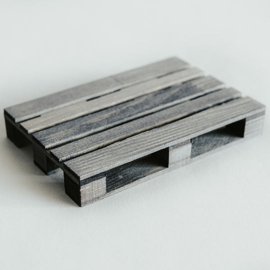 Handcrafted wooden pallet coaster in a gray-stained finish, featuring a smooth texture and detailed craftsmanship, displayed on a light surface.