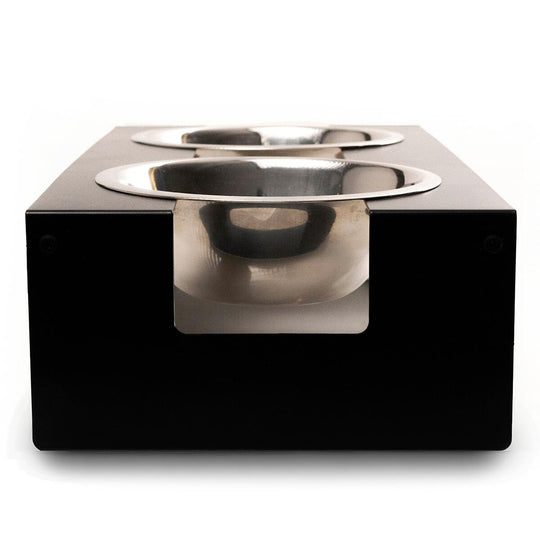 Front view of an elevated dog feeder featuring a minimalist black metal frame, housing two stainless steel bowls in a modern, square design.