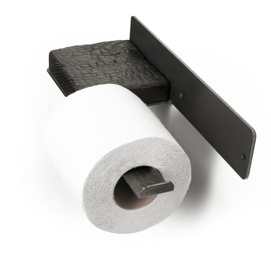 Close-up of a wall-mounted burned wood and metal toilet paper holder, holding a single roll of toilet paper, showcasing an industrial look.