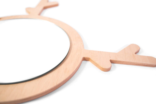 Close-up side view of a deer-shaped wooden mirror with antlers, featuring a smooth, layered wood frame and a round reflective surface.