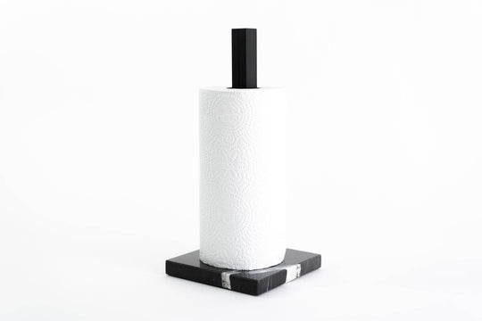 Paper towel holder featuring a black marble base with white veining and a black metal stand, holding a white paper towel roll, designed for a sleek and contemporary look.