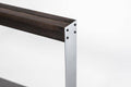 Close-up of a minimalist knife holder featuring a dark wooden top, sleek silver metal frame, and visible black screws securing the structure.