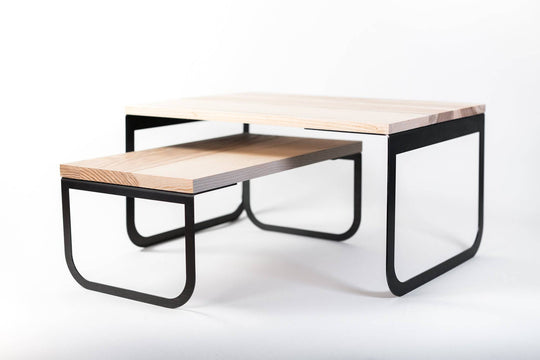 Modern industrial coffee table featuring dual-tier natural wood surfaces and sleek black metal legs, emphasizing minimalist and contemporary design elements.