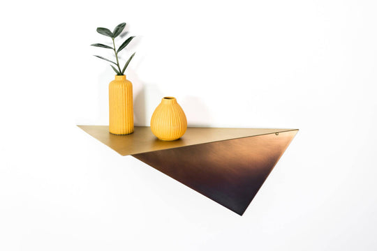 Modern triangular wall shelf with a brushed copper finish, displaying two textured yellow vases and a plant for a stylish, minimalist look.