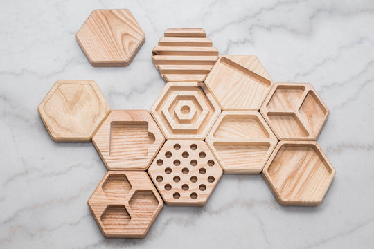 Hexagonal wooden desk organizers arranged in a modular layout on a marble surface.