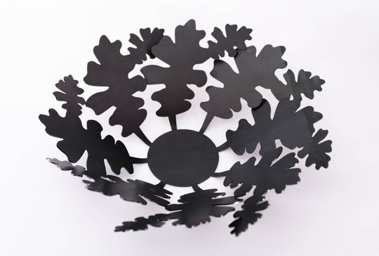 Black metal bowl with intricate oak leaf-shaped cutouts, showcasing a modern and elegant design.