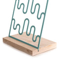 Turquoise wave-patterned metal jewelry holder on a natural wood base.