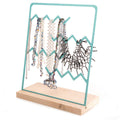 Turquoise zigzag metal jewelry holder displayed on a wooden base, adorned with various necklaces.