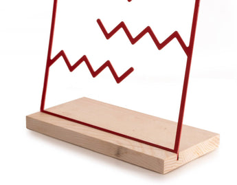 Red zigzag metal jewelry holder on a natural wood base, simple and minimalistic design.