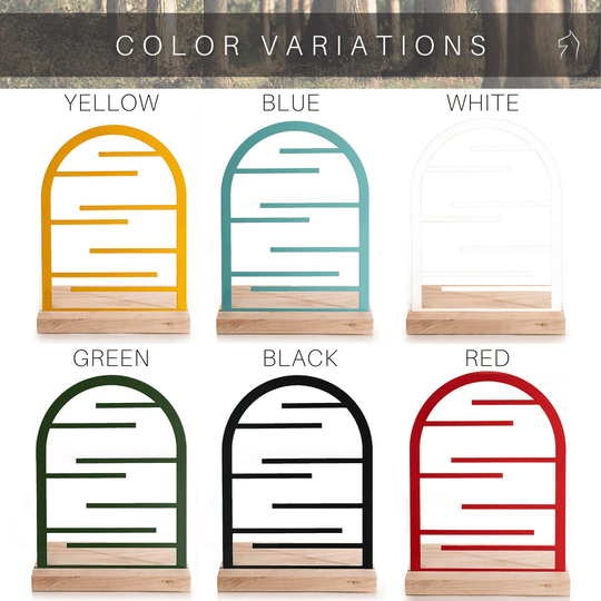 Jewelry holders available in six color variations: yellow, blue, white, green, black, and red. Each holder features an arched frame with horizontal bars, made from durable steel and set on a wooden base.