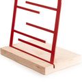 Close-up of a red jewelry holder with a wooden base, featuring horizontal bars for hanging accessories.