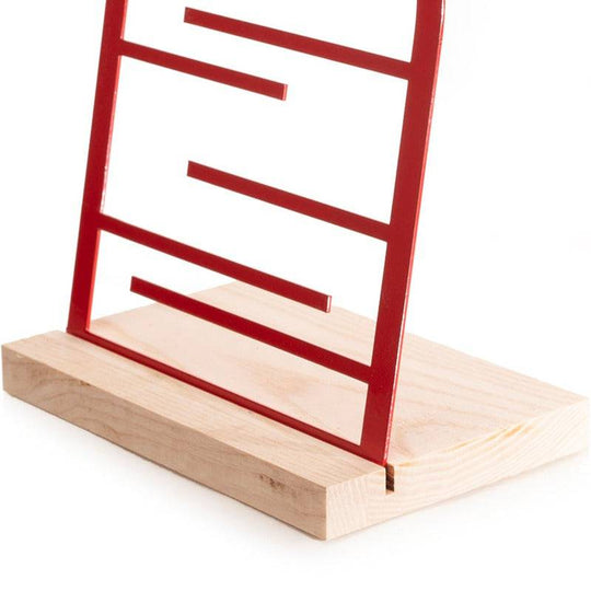 Close-up of a red jewelry holder with a wooden base, featuring horizontal bars for hanging accessories.