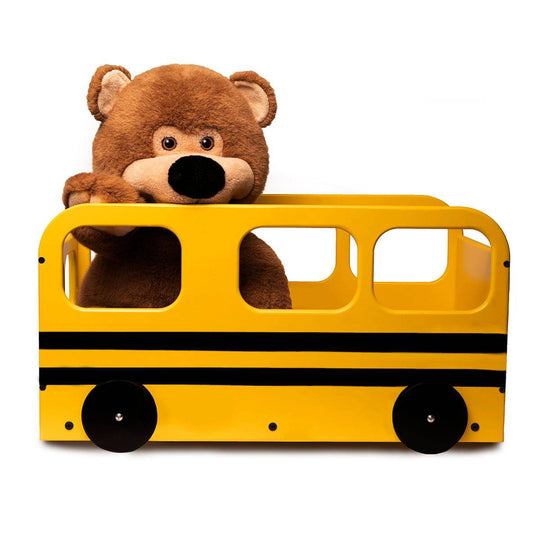 A large brown teddy bear sitting inside a bright yellow, school bus-inspired wooden storage box with black wheels and stripes.