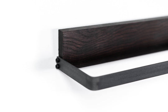Close-up of a black metal towel rack with a dark wooden backing, featuring a minimalist, sleek design.