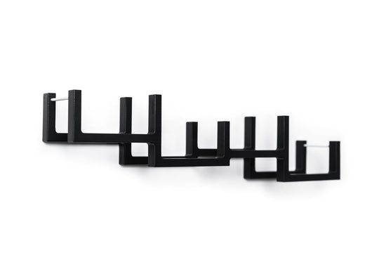 Close-up of a black geometric wall-mounted toilet paper holder with a series of square frames and metal bars to hold multiple rolls.