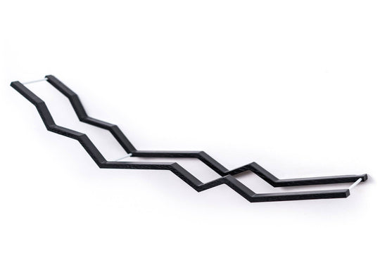 Close-up of a black wooden zigzag toilet paper holder with metal bars, showcasing the holder’s unique zigzag pattern and textured design.